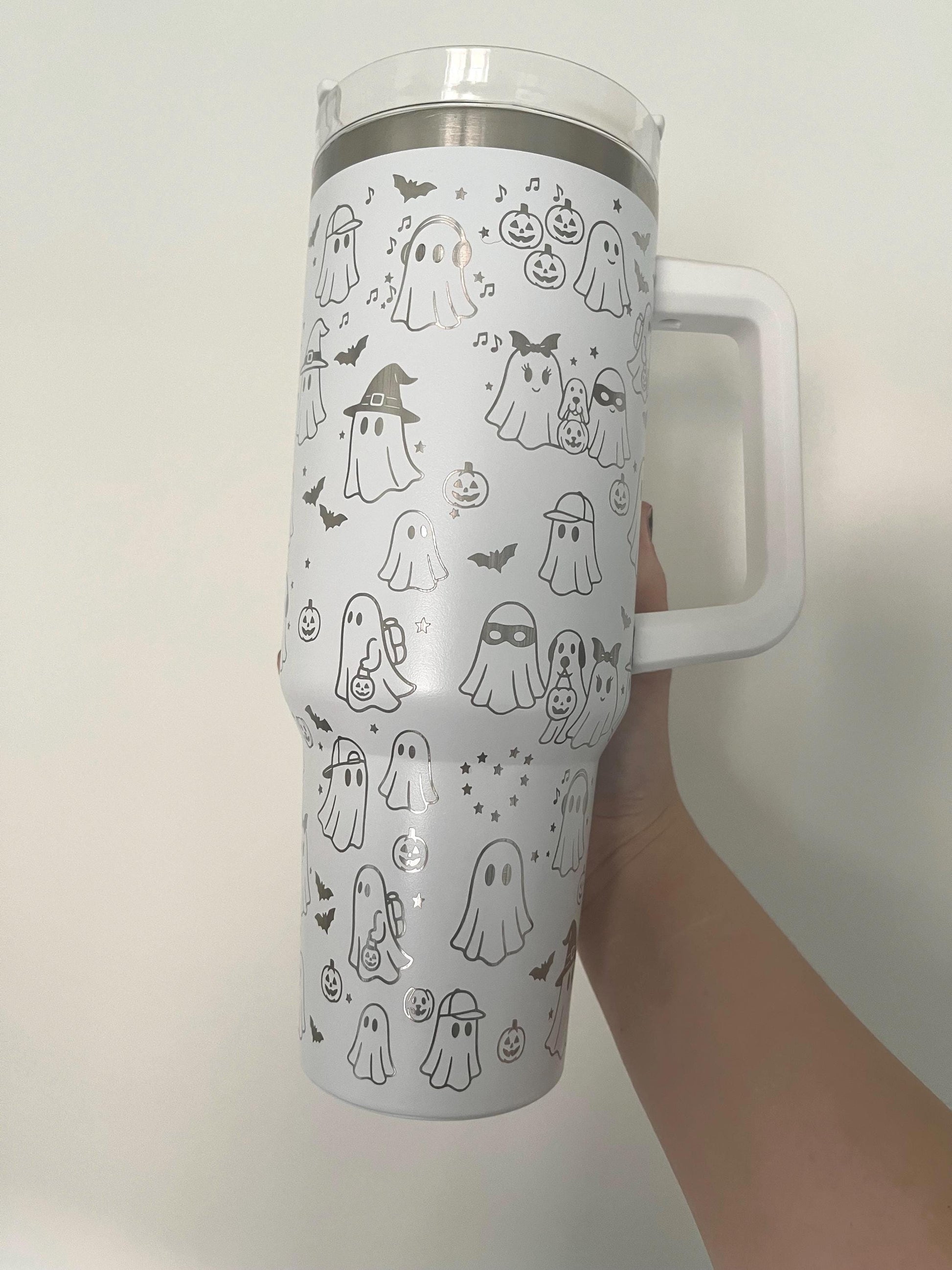 white 40oz tumbler with handle laser engraved with cute spooky sheet ghosts in costumes
